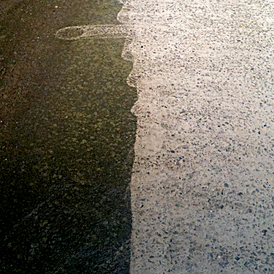 A concrete driveway part way through pressure cleaning.