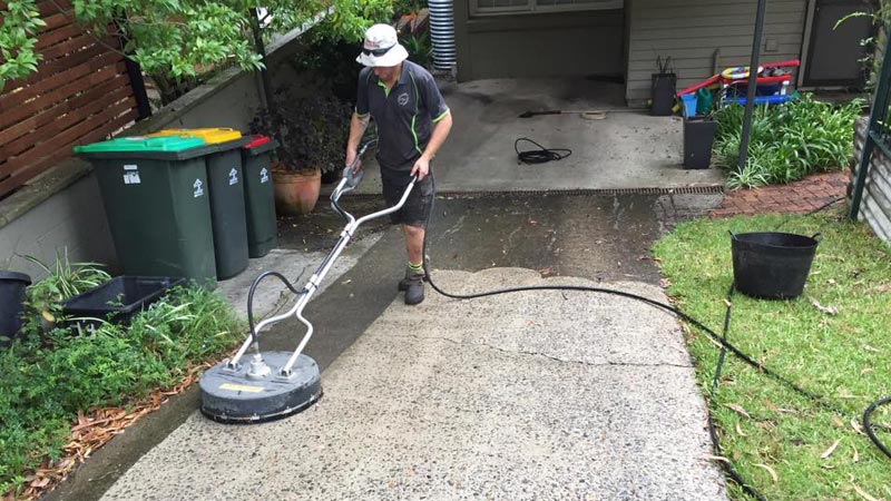 A driveway being cleaned with a rotary surface cleaner.